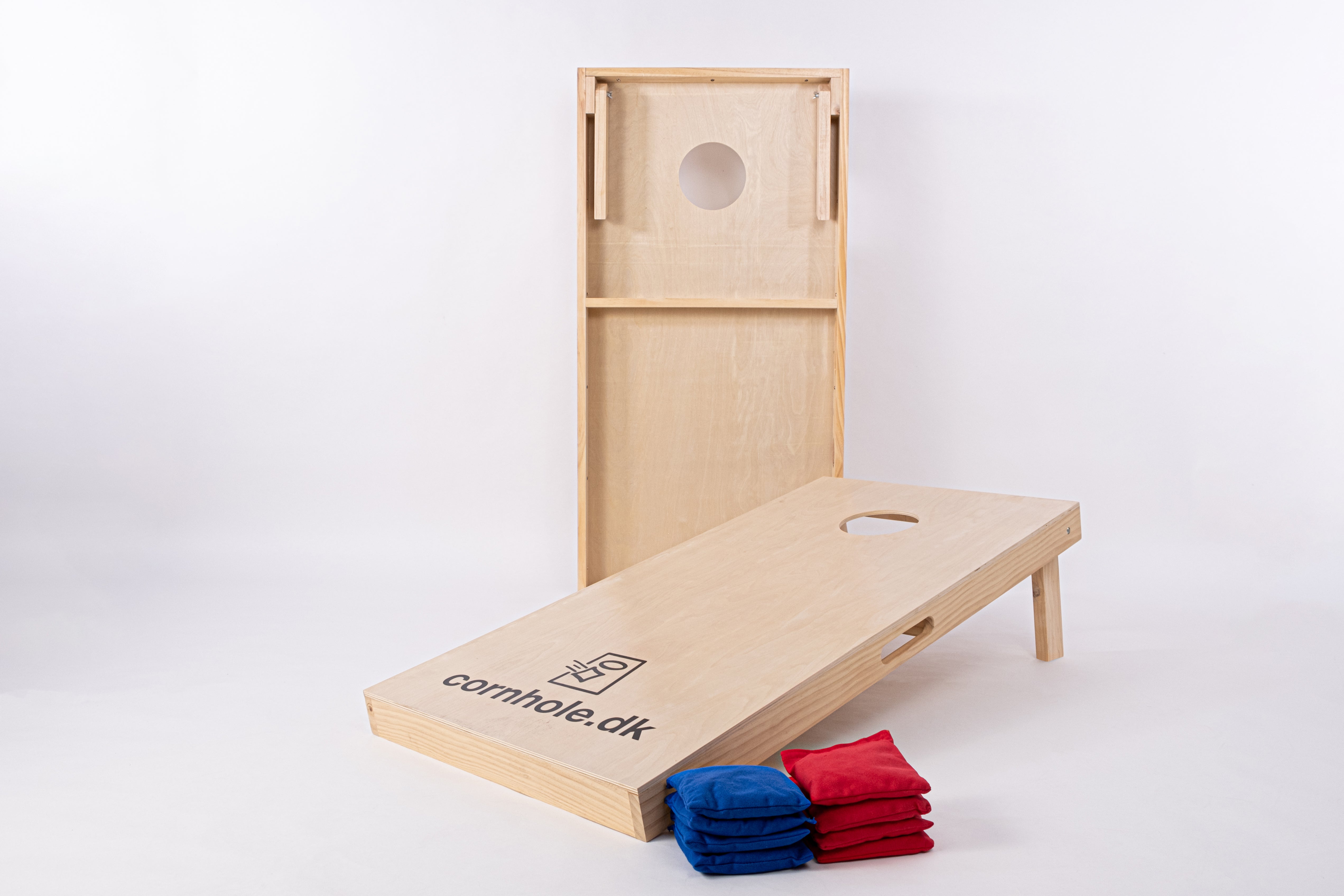 CornholesÊt i de officielle mÄl 120x60 cm fra cornhole.dk med 8 stk. kasteposer i blÄ og rÞd farve. Billedet er taget i et photostudie med god belysning, og man kan se den hÞje kvalitet og flotte trÊ.